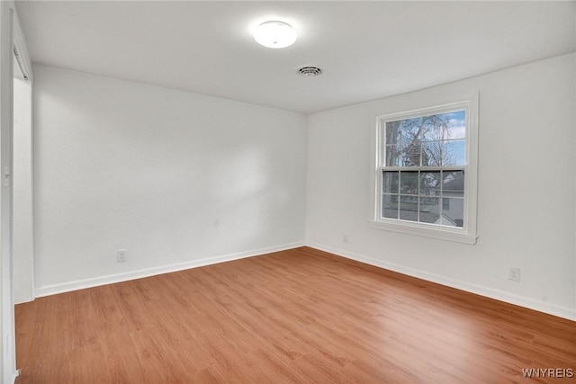 empty room with visible vents, baseboards, and wood finished floors