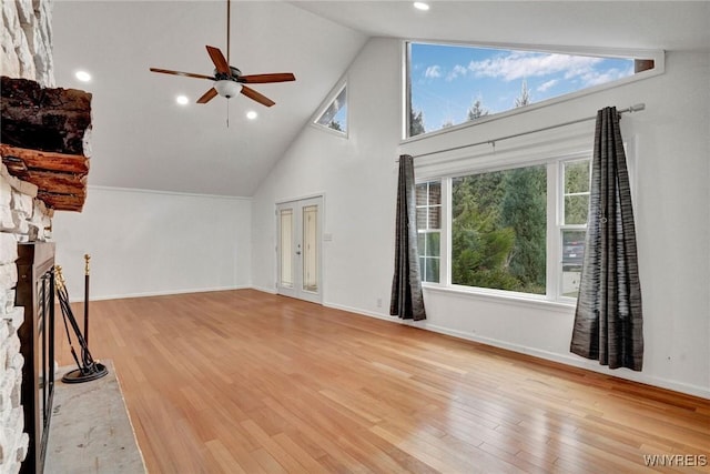 unfurnished living room featuring a stone fireplace, ceiling fan, high vaulted ceiling, and wood finished floors