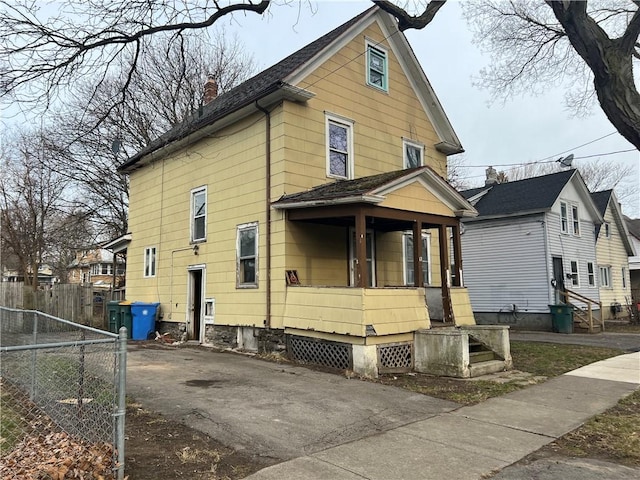 exterior space featuring a porch, fence, driveway, and a chimney