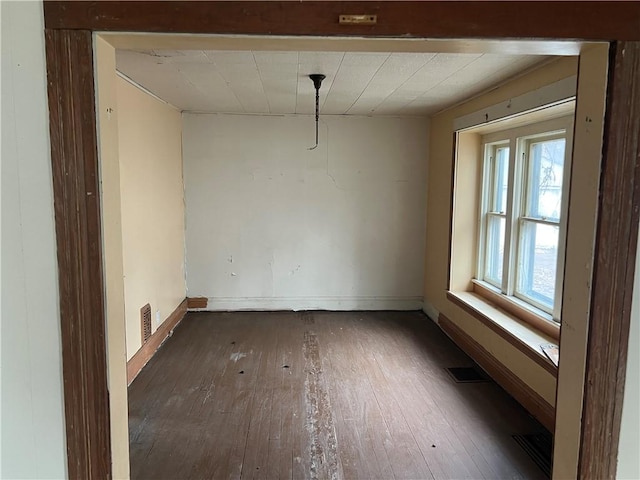 spare room featuring hardwood / wood-style floors, baseboards, and visible vents