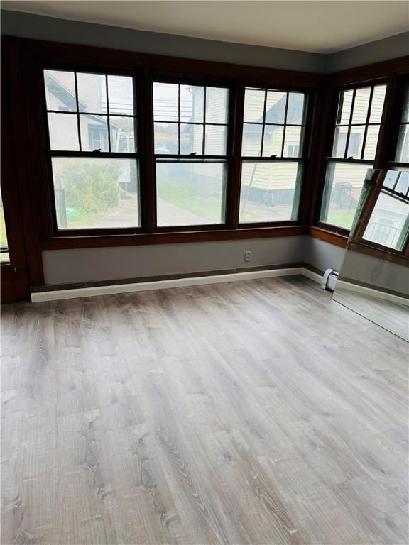 spare room featuring baseboard heating, baseboards, and wood finished floors
