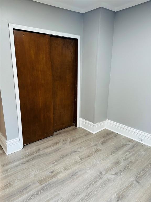 unfurnished bedroom with a closet, baseboards, and light wood finished floors