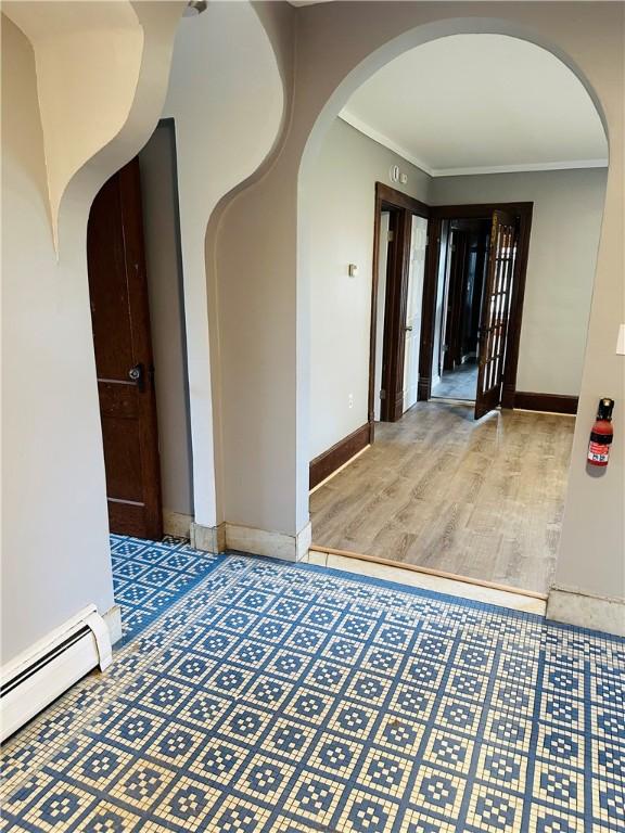 corridor with baseboards, arched walkways, ornamental molding, baseboard heating, and wood finished floors