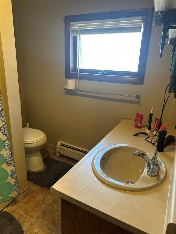 bathroom featuring toilet, tile patterned floors, a baseboard heating unit, and vanity