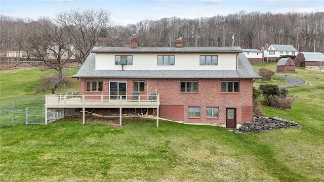 rear view of house with a chimney, a lawn, fence, and brick siding