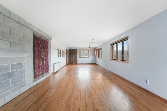 unfurnished living room featuring light wood-style floors and radiator heating unit