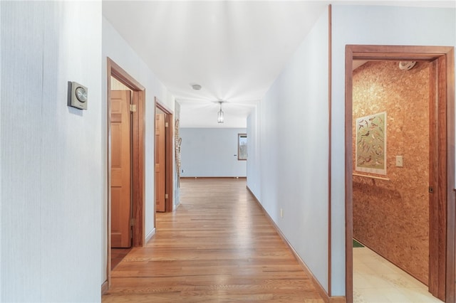 hall featuring light wood finished floors and baseboards