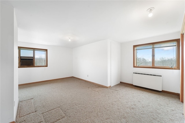 carpeted empty room featuring radiator heating unit, baseboards, and plenty of natural light