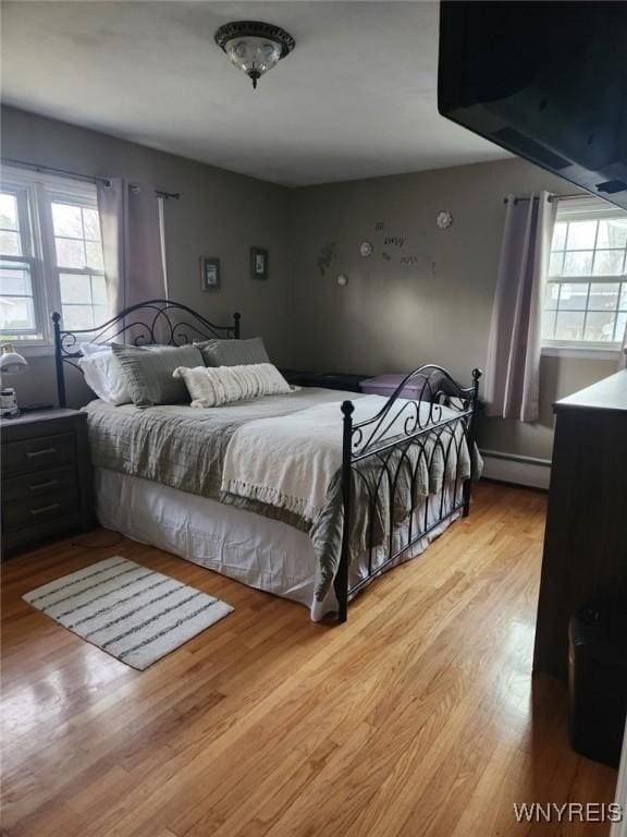 bedroom with a baseboard radiator and wood finished floors