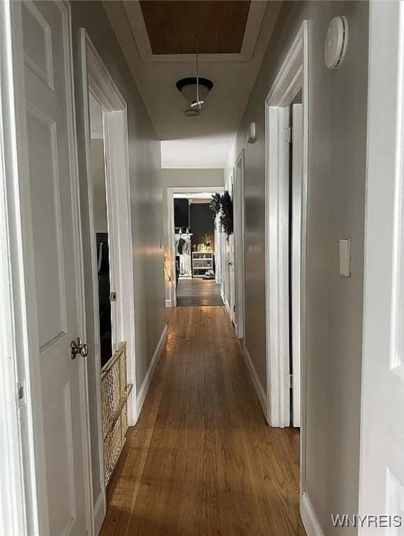 corridor featuring baseboards, attic access, and dark wood finished floors