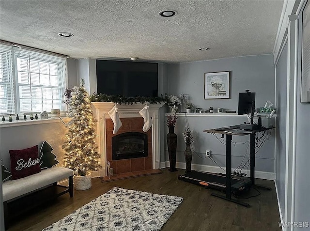 interior space featuring a fireplace, a textured ceiling, baseboards, and wood finished floors