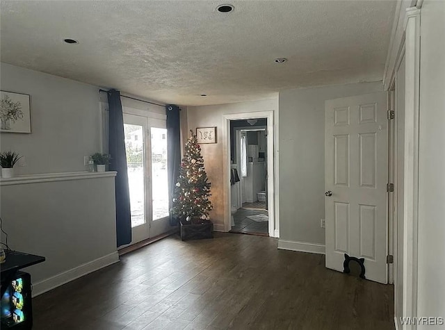 interior space featuring dark wood-style floors, a textured ceiling, baseboards, and french doors