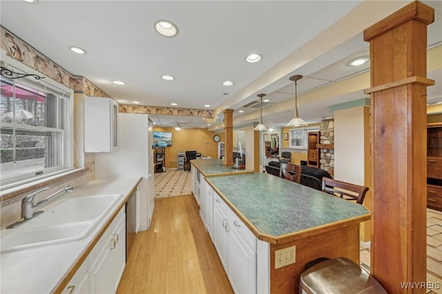 1465 Genesee St, Pembroke, NY 14036 - kitchen featuring light wood finished floors, white cabinets, open floor plan, and a sink
