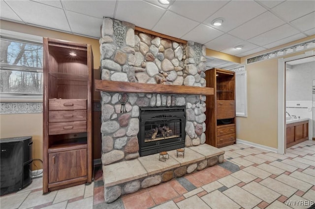 1465 Genesee St, Pembroke, NY 14036 - unfurnished living room with a paneled ceiling, a stone fireplace, and baseboards
