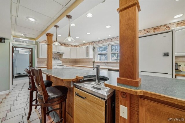 1465 Genesee St, Pembroke, NY 14036 - kitchen featuring a breakfast bar area, decorative backsplash, ornate columns, and white range with gas cooktop