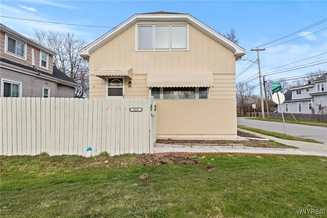 bungalow featuring fence and a front lawn