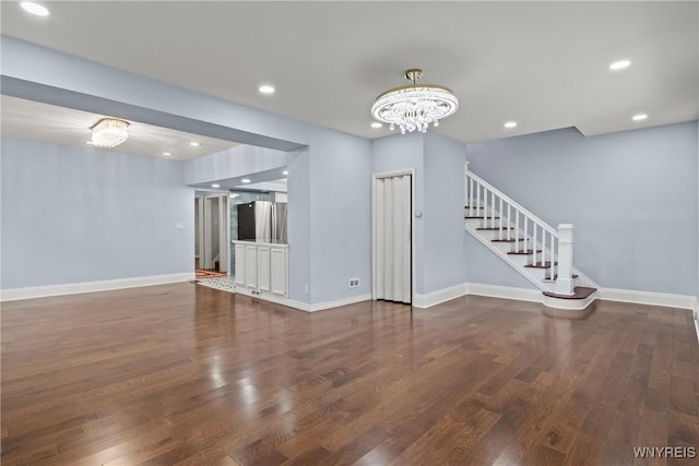 unfurnished living room with wood finished floors, a notable chandelier, and baseboards