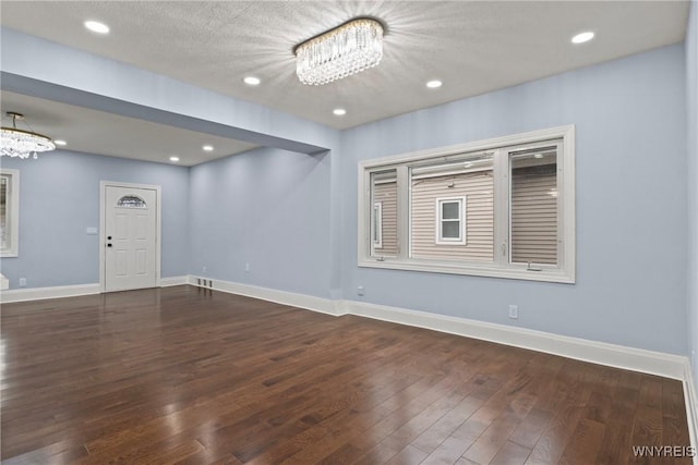 unfurnished room featuring hardwood / wood-style floors, an inviting chandelier, baseboards, and recessed lighting