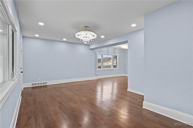 empty room featuring wood finished floors, a notable chandelier, visible vents, and recessed lighting