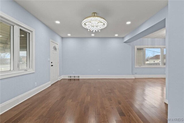unfurnished room featuring a chandelier, visible vents, baseboards, and wood finished floors