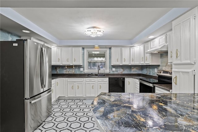 kitchen with white cabinets, appliances with stainless steel finishes, under cabinet range hood, a sink, and backsplash