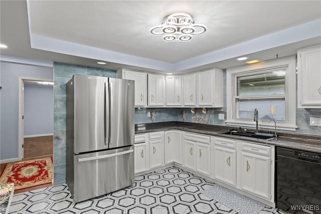 kitchen with freestanding refrigerator, white cabinetry, black dishwasher, a sink, and dark countertops