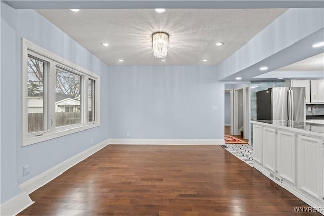 unfurnished dining area with a notable chandelier, baseboards, recessed lighting, dark wood-style floors, and a textured ceiling
