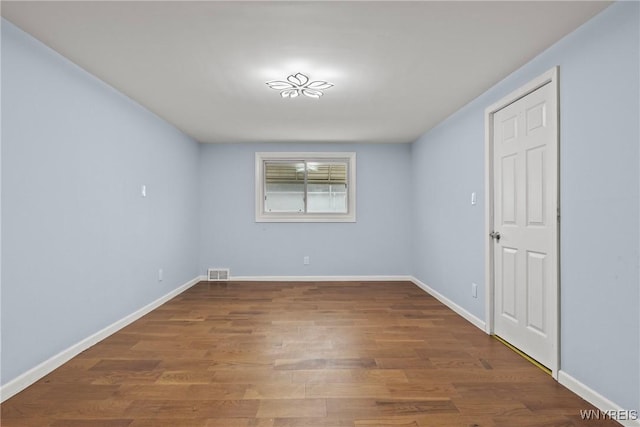 spare room featuring wood finished floors, baseboards, and visible vents