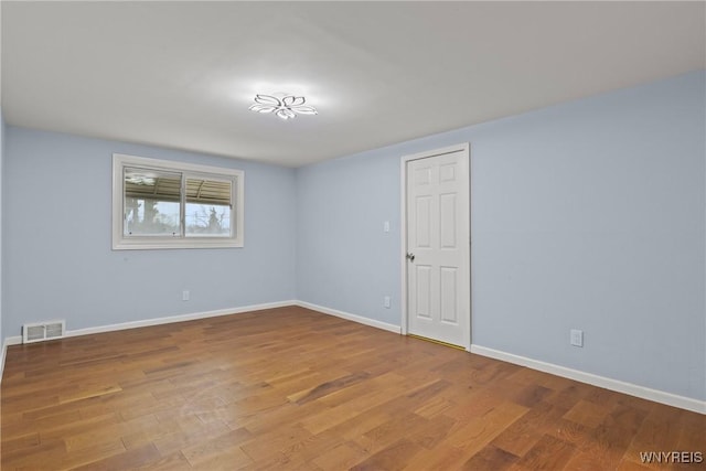 empty room featuring visible vents, baseboards, and wood finished floors