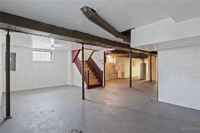 basement featuring water heater, stairway, and electric panel