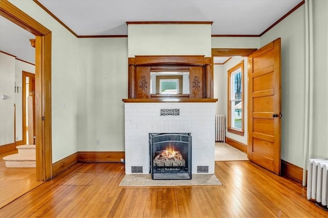 unfurnished living room with crown molding, radiator heating unit, and hardwood / wood-style flooring