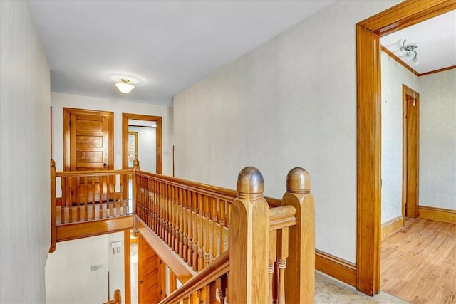 hall with wood finished floors, baseboards, and an upstairs landing