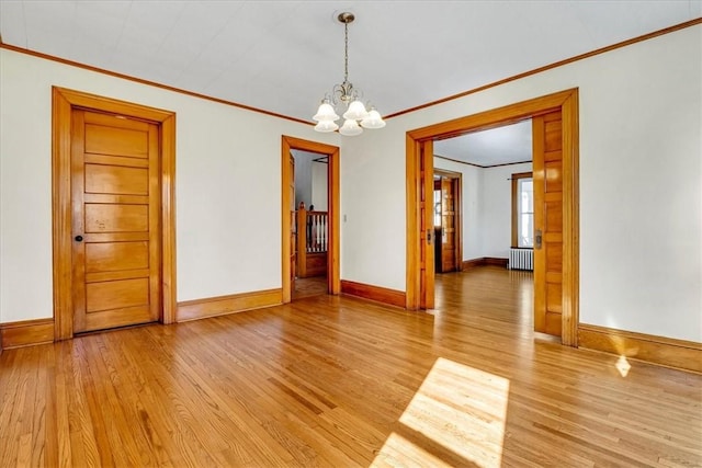 spare room with baseboards, a chandelier, crown molding, radiator heating unit, and light wood-style floors