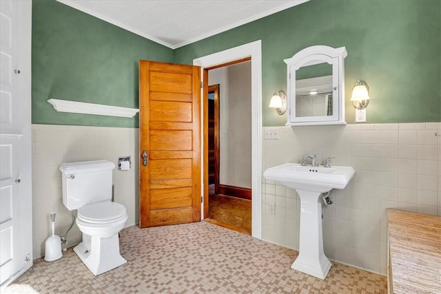 bathroom featuring toilet, tile patterned floors, a wainscoted wall, and tile walls