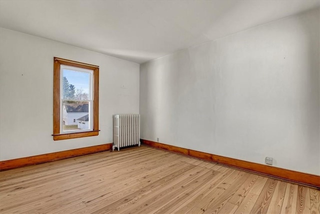 unfurnished room featuring light wood-style floors, radiator heating unit, and baseboards