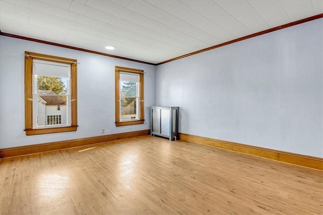 empty room featuring ornamental molding, baseboards, and wood finished floors