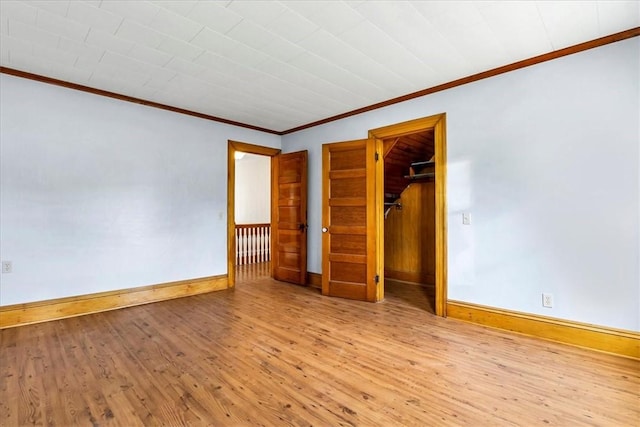 unfurnished bedroom with crown molding, a closet, baseboards, and wood finished floors