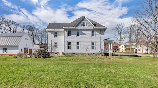 rear view of property featuring a shingled roof and a lawn