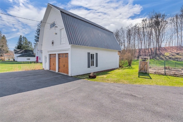 view of home's exterior with a garage, a gambrel roof, metal roof, and a lawn