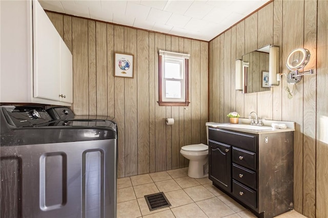 bathroom with tile patterned floors, toilet, wood walls, visible vents, and washer and dryer