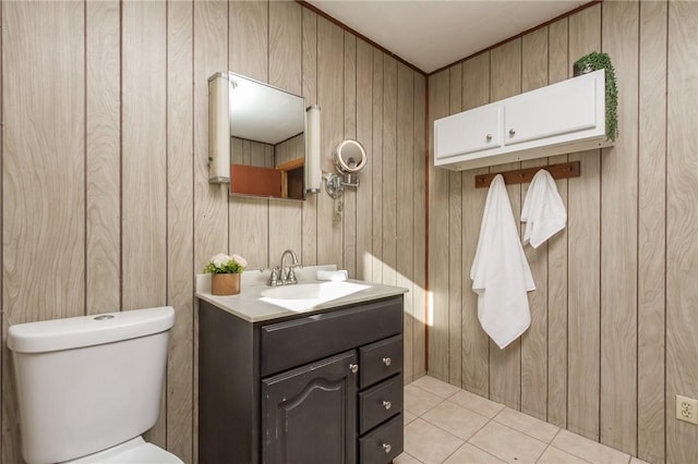 half bathroom featuring wood walls, toilet, vanity, and tile patterned flooring
