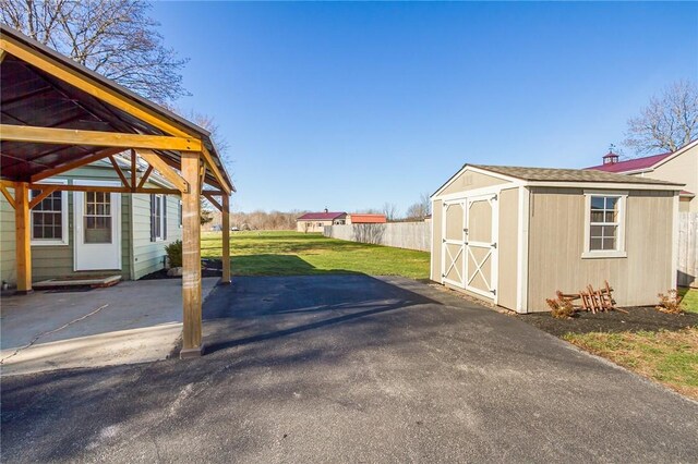 view of yard featuring an outdoor structure, fence, and a storage unit