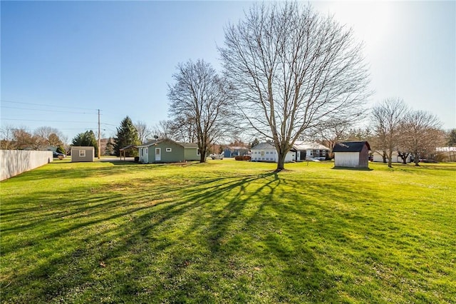 view of yard featuring a shed, a residential view, fence, and an outbuilding