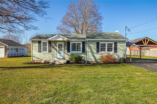 single story home featuring aphalt driveway, a carport, fence, and a front lawn