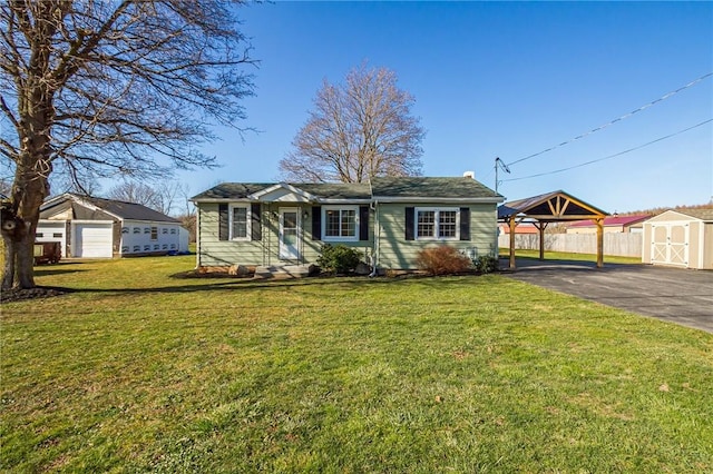 view of front facade featuring an outdoor structure, a detached carport, a front lawn, a storage shed, and fence