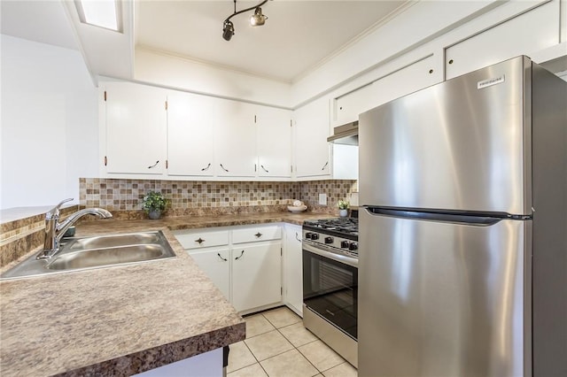 kitchen with tasteful backsplash, white cabinetry, under cabinet range hood, appliances with stainless steel finishes, and a sink