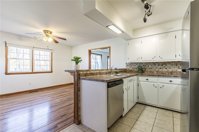kitchen with white cabinetry, a ceiling fan, dark countertops, dishwasher, and a sink