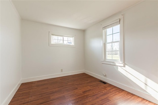 empty room featuring visible vents, baseboards, and wood finished floors