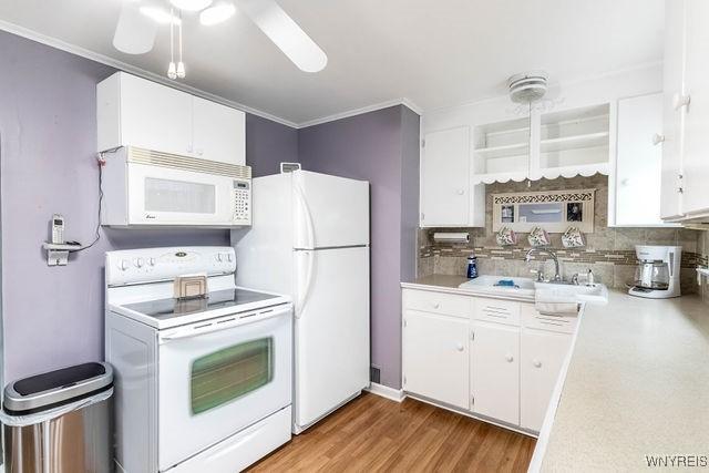 kitchen with white cabinets, light countertops, and white appliances