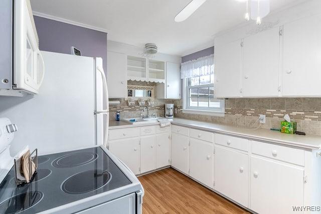 kitchen featuring freestanding refrigerator, a sink, light countertops, range with electric cooktop, and decorative backsplash